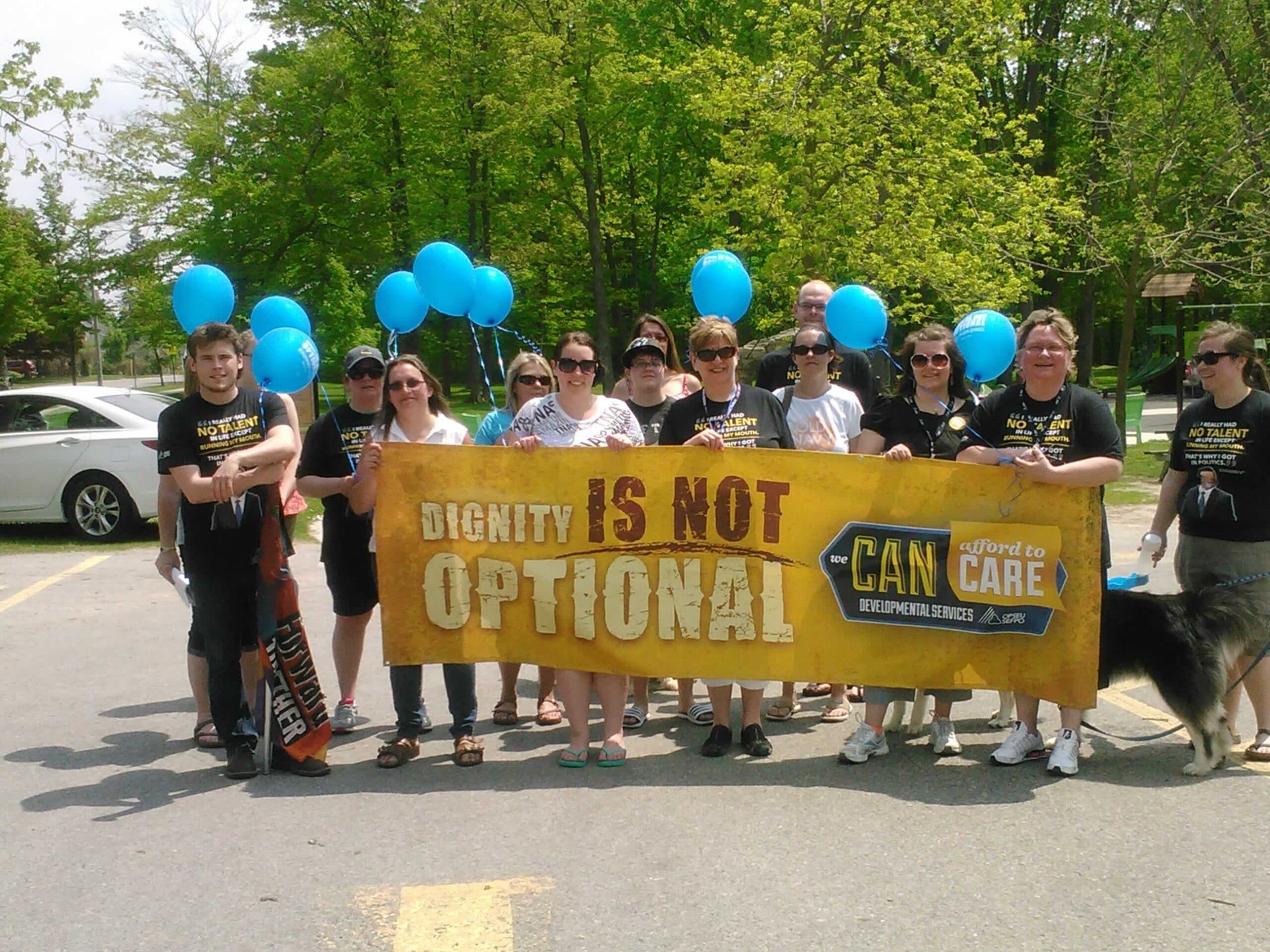 OPSEU members hold up balloons & banner that says: Dignity is not optional
