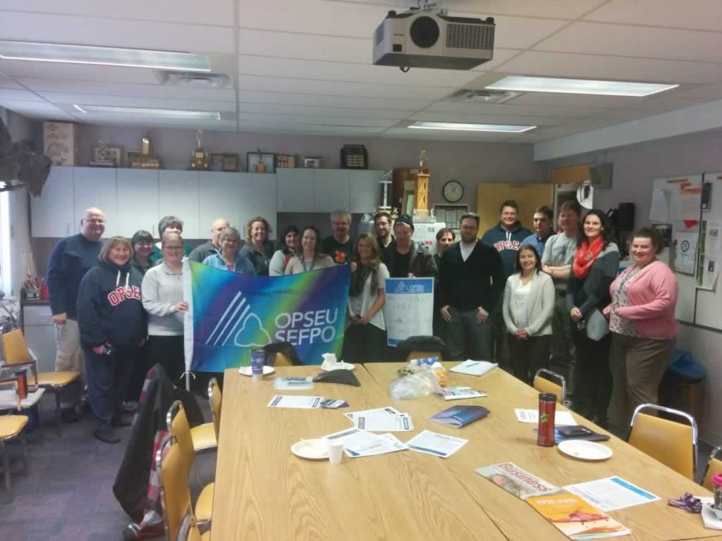 OPSEU members pose together, holding up a colourful OPSEU flag during the Sioux lookout