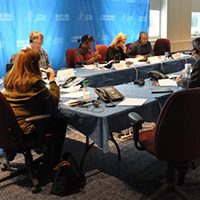 OPSEU members and staff sitting at at a table wearing headsets during a Corrections teletown hall