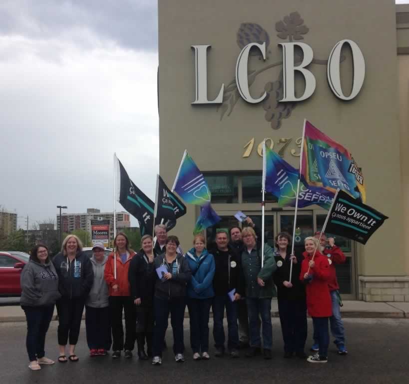 OPSEU members hold flags during a rally outside and LCBO in London.