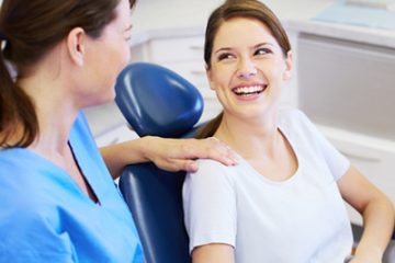 Woman in dentist's chair smiling at a dentist.