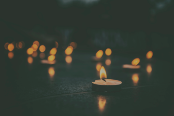 A number of small candles burning in darkness