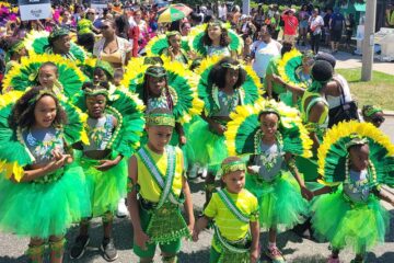 Large group of children wear bright greens and yellows for Carnival