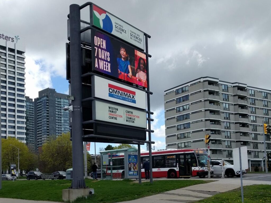 Ontario Science Centre street sign with bus stop next to it, with a Toronto Transit bus stopped at it.