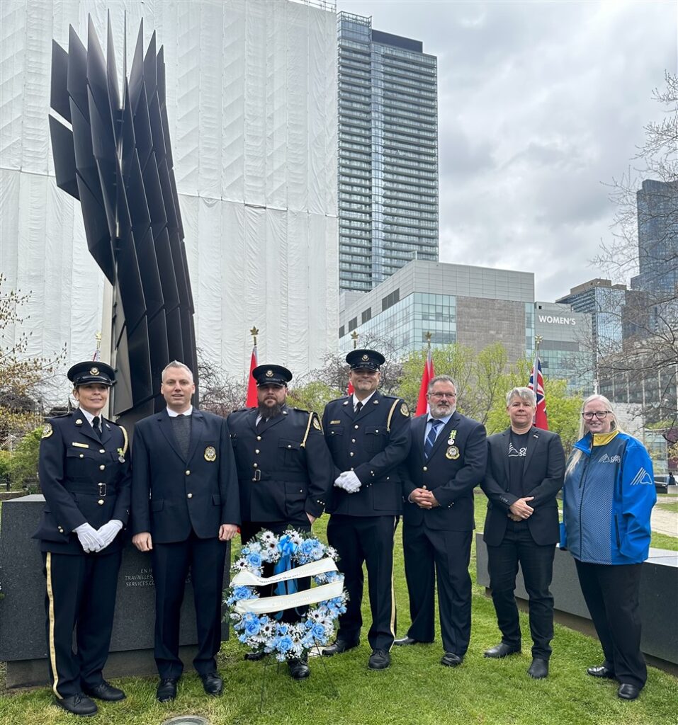 Group picture of Correctional Bargaining Unit leaders standing with President JP Hornick and 1st VP/Treasurer Laurie Nancekivell in front of the Correctional Workers' Monument with a blue memorial wreath